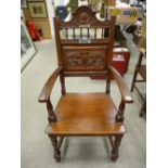 A 1914 OAK EISTEDDFOD CHAIR having a shell carved top rail, spindle gallery and lower leaf carved