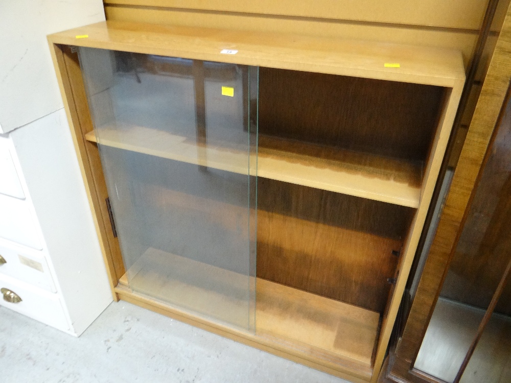 A neat light oak sliding glass door low bookcase