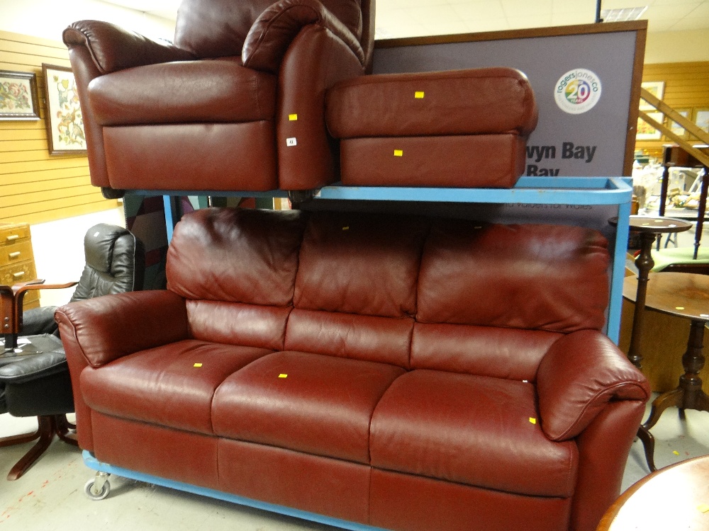 A good quality modern dark red leather three seater sofa together with a matching armchair &
