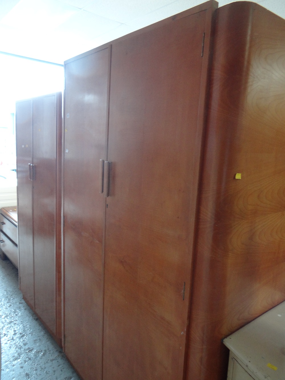 Two Art Deco-style veneered lightwood wardrobes together with a low two-drawer chest of drawers