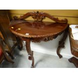 A nicely carved mahogany demi-lune hall table together with a carved rail back