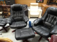 A pair of black leather swivel armchairs together with matching footstools