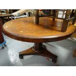 An antique circular Regency-style mahogany dining table on central column support and tripod bun