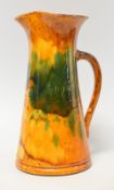 AN EWENNY POTTERY FLOWER JUG in a mottled orange and green glaze and inscribed 'Blodau Hyfrd' (sic),
