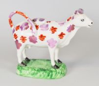 A SWANSEA COW CREAMER typically sponge decorated in lustre and standing on a green painted 'grass'