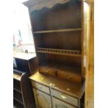 A reproduction oak dresser of small proportions with cupboard & drawer base and rack with two base