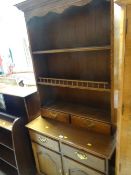 A reproduction oak dresser of small proportions with cupboard & drawer base and rack with two base