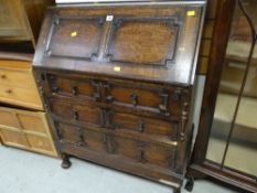 A vintage oak Jacobean-style three-drawer sloped bureau