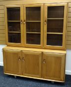 AN ERCOL BLONDE LOUNGE UNIT composed of a base with three cupboards and a top of three glazed