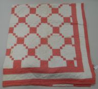 AN EARLY TWENTIETH CENTURY HAND STITCHED PINK & WHITE BED QUILT with striped pattern one side and g