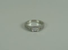 A FINE QUALITY EMERALD-CUT DIAMOND RING IN PLATINUM SETTING with three smaller diamonds to each