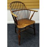 AN ELM WINDSOR ELBOW CHAIR with two-stage spindle & hoop back and having turned supports