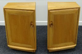 A PAIR OF ERCOL BEDSIDE CABINETS each having single doors with shelved interior in blonde wood