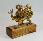 A LIMITED EDITION POLISHED BRONZE WELSH DRAGON (4/250) standing on an oak block plinth, together
