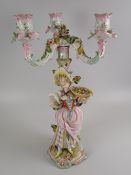 A SITZENDORF PORCELAIN FIGURAL CANDLEHOLDER in gaudy coloured glazes with three branches, the figure