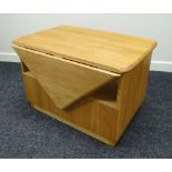 AN ERCOL BLONDE TABLE with single drop leaf, middle cavity and drawer, 73cms wide