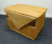 AN ERCOL BLONDE TABLE with single drop leaf, middle cavity and drawer, 73cms wide