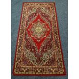 A BRITISH-MADE RED GROUND RUG with traditional medallion design. 180 x 90cms