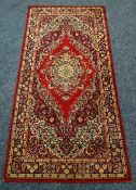 A BRITISH-MADE RED GROUND RUG with traditional medallion design. 180 x 90cms