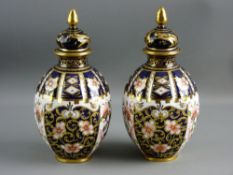 A PAIR OF ROYAL CROWN DERBY GLOBULAR VASES with deep blue ground and gilt knopped lids, 18 cms high