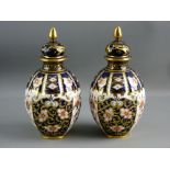 A PAIR OF ROYAL CROWN DERBY GLOBULAR VASES with deep blue ground and gilt knopped lids, 18 cms high