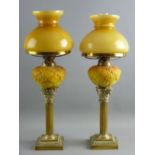 A PAIR OF SQUARE BASED BRASS SHORT STEMMED CORINTHIAN COLUMN OIL LAMPS with milk glass yellow leaf