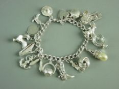A SILVER CHARM BRACELET with padlock and over fifteen charms, 47 grms