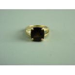 A NINE CARAT GOLD SMOKEY QUARTZ DRESS RING having a split shank and a square cut quartz, 5 grms