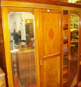 AN EDWARDIAN INLAID MAHOGANY TRIPLE WARDROBE having twin mirrored outer doors with shaped bevelled