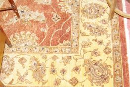 AN INDIAN JAIPUR HAND KNOTTED WOOL PILE CARPET, red ground with a wide cream border having a