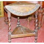 A CIRCA 1930 CARVED OAK CRICKET TABLE in triangular form with triple flaps opening to form a