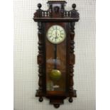 A WALNUT CASED VIENNA STYLE WALL CLOCK, twin weight pendulum driven movement striking on a coiled