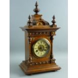 A CIRCA 1900 GERMAN OAK CASED MANTEL CLOCK, architecturally styled with finial caps and decorative