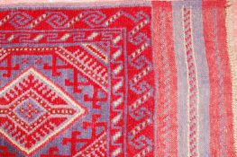 A MESHWANI RUNNER, a deep red ground woven tribal runner with repeated diamond pattern and wide