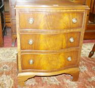 A NEAT REPRODUCTION MAHOGANY SERPENTINE FRONT THREE DRAWER CHEST with brass ring handles and on
