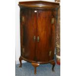 A GEORGIAN MAHOGANY BOW FRONT FLOORSTANDING CORNER CABINET, the railback top over twin doors with