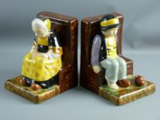 A PAIR OF QUIMPER POTTERY BOOKENDS modelled as a young girl and boy seated on benches, the girl with