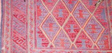 A TRIBAL KAZAK RUG, deep red ground woollen woven rug with central repeated diamond pattern and