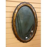 A GILT CHINOISERIE DECORATED OVAL WALL MIRROR having shaped edge moulding and beaded interior rim to