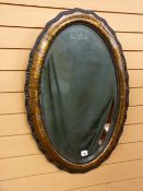 A GILT CHINOISERIE DECORATED OVAL WALL MIRROR having shaped edge moulding and beaded interior rim to