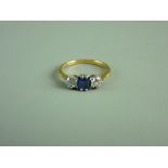 AN EIGHTEEN CARAT GOLD LADY'S DRESS RING having a centre square cut sapphire with two flanking