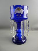 A VICTORIAN BLUE GLASS LUSTRE with castellated top and enamel painted floral band on a shaped stem