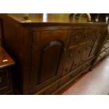 A reproduction hardwood multi-drawer sideboard with twin cupboard doors