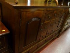 A reproduction hardwood multi-drawer sideboard with twin cupboard doors