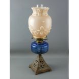 A VICTORIAN OIL LAMP with iron base, blue glass reservoir and milk glass shade