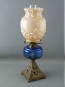 A VICTORIAN OIL LAMP with iron base, blue glass reservoir and milk glass shade