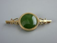 A NINE CARAT GOLD BROOCH with circular jade or green agate tablet, 6 grms gross