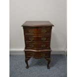 A REPRODUCTION MAHOGANY SERPENTINE FRONT THREE DRAWER CHEST on a slightly stepped base with a