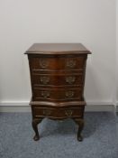 A REPRODUCTION MAHOGANY SERPENTINE FRONT THREE DRAWER CHEST on a slightly stepped base with a