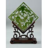 A CARVED GREEN JADE TABLE SCREEN on wooden stand, the pierced panel depicting a dragon and phoenix